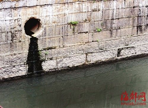 內河一處排污口，正在流出墨黑色污水。