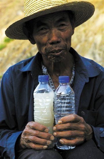 3月21日，一位村民拿著兩瓶水，里面是小江水和普通礦泉水的對比。